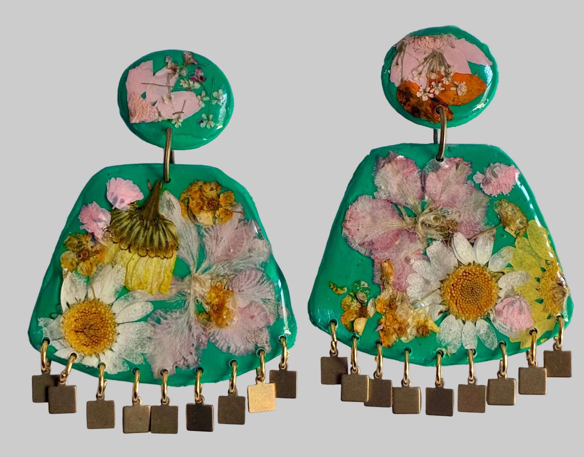 Floral earrings with green background and gold accents on a white surface