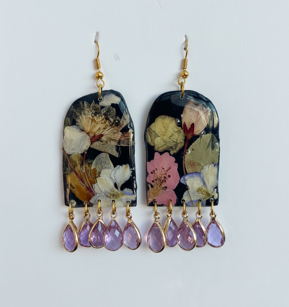 Floral earrings with teardrop-shaped purple stones on a white background