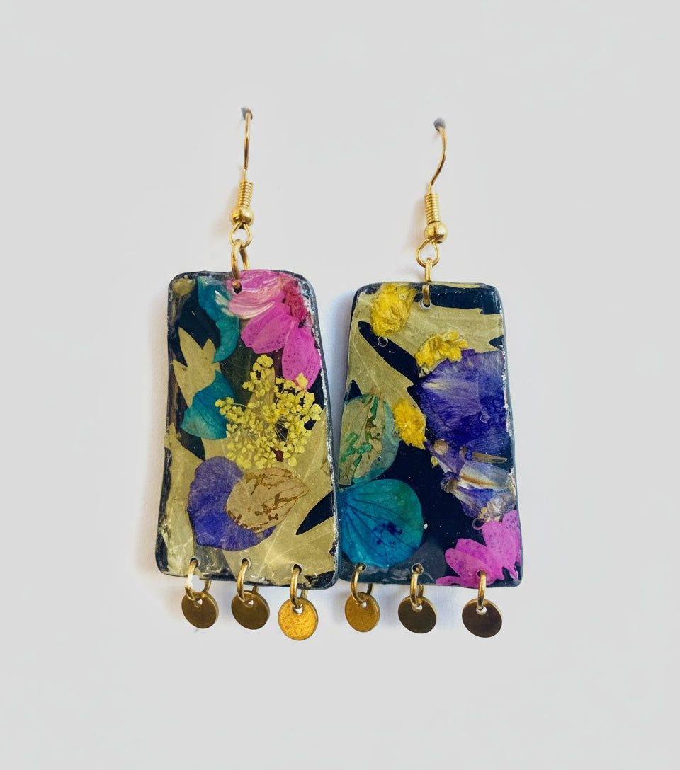 Colorful floral earrings with hanging charms on a black background