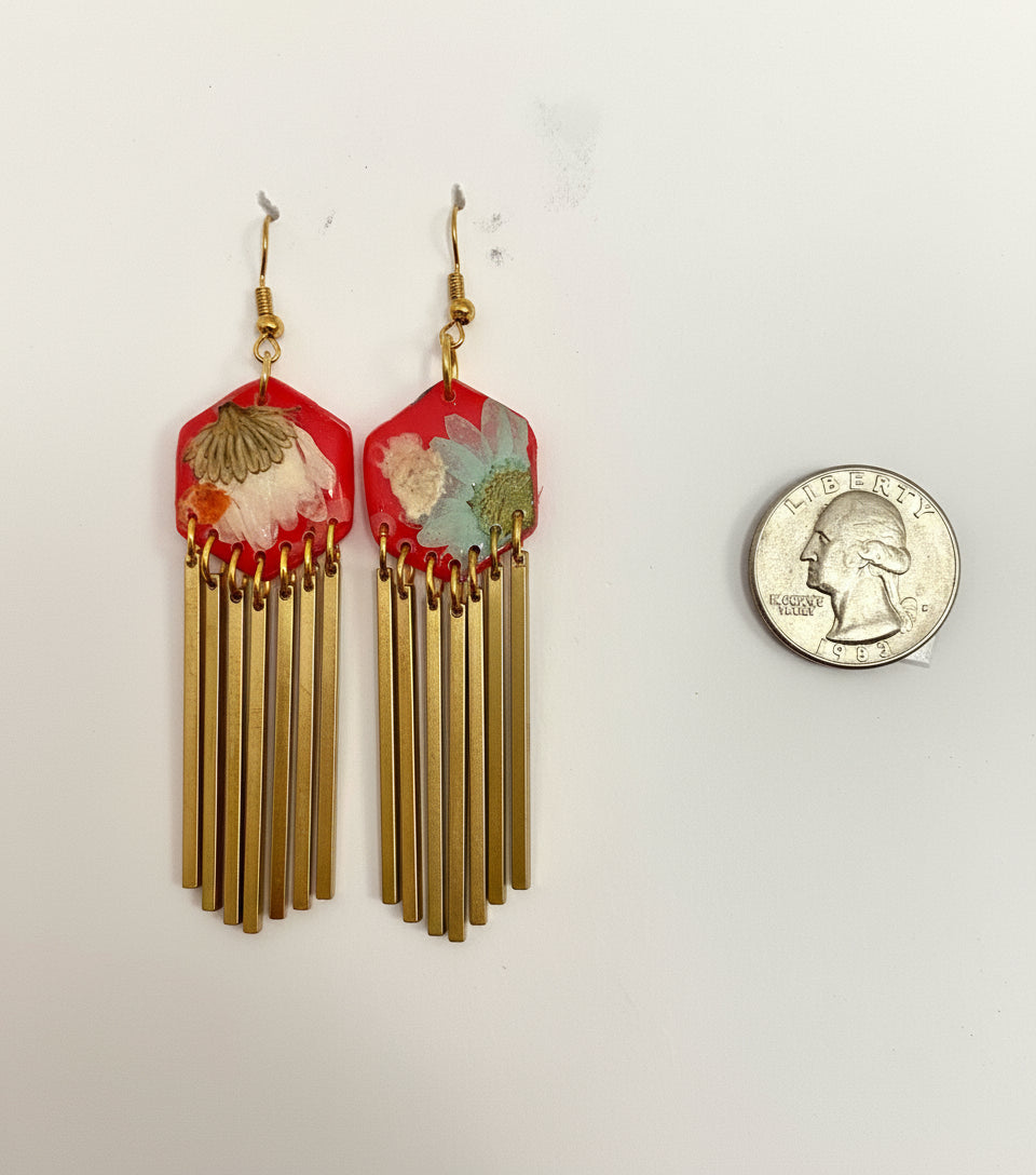 Pair of earrings with red floral accents and gold fringe, next to a quarter for scale.