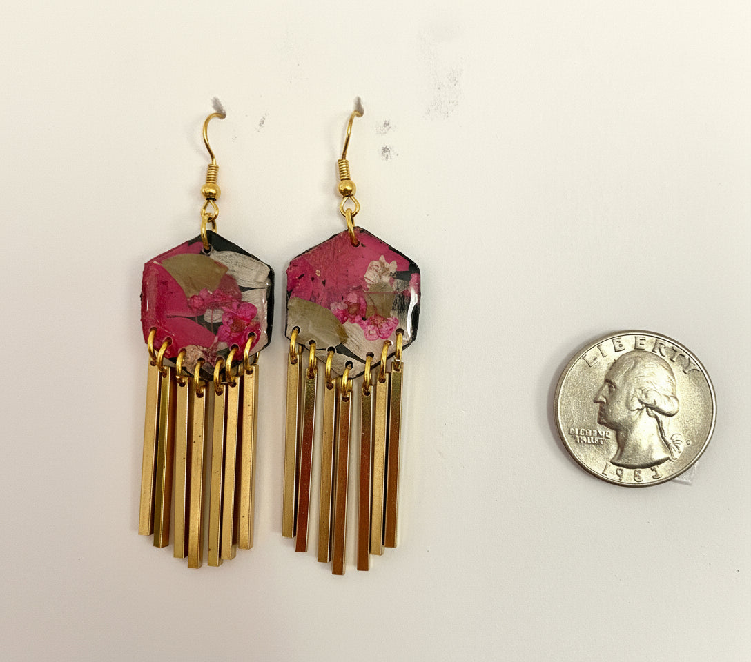 Pair of earrings with pink and gold design, next to a quarter for scale.