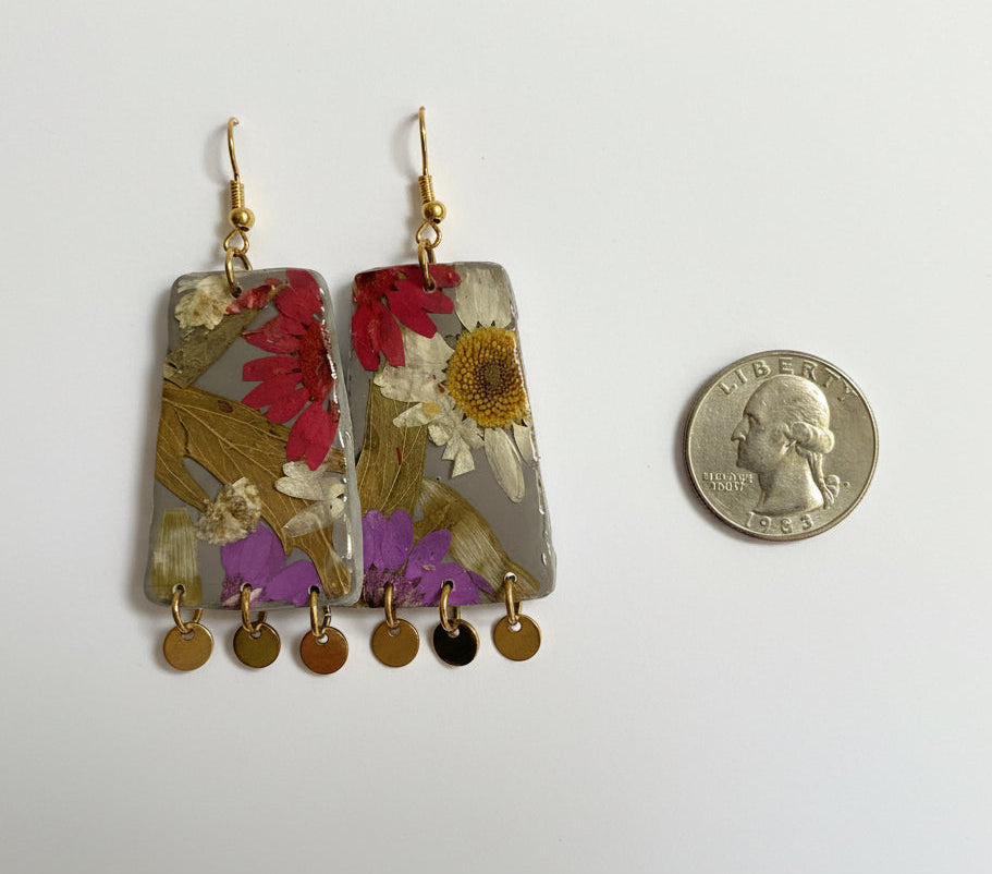 Trapezoid earrings with floral design and gold beads next to a quarter for scale on a white background